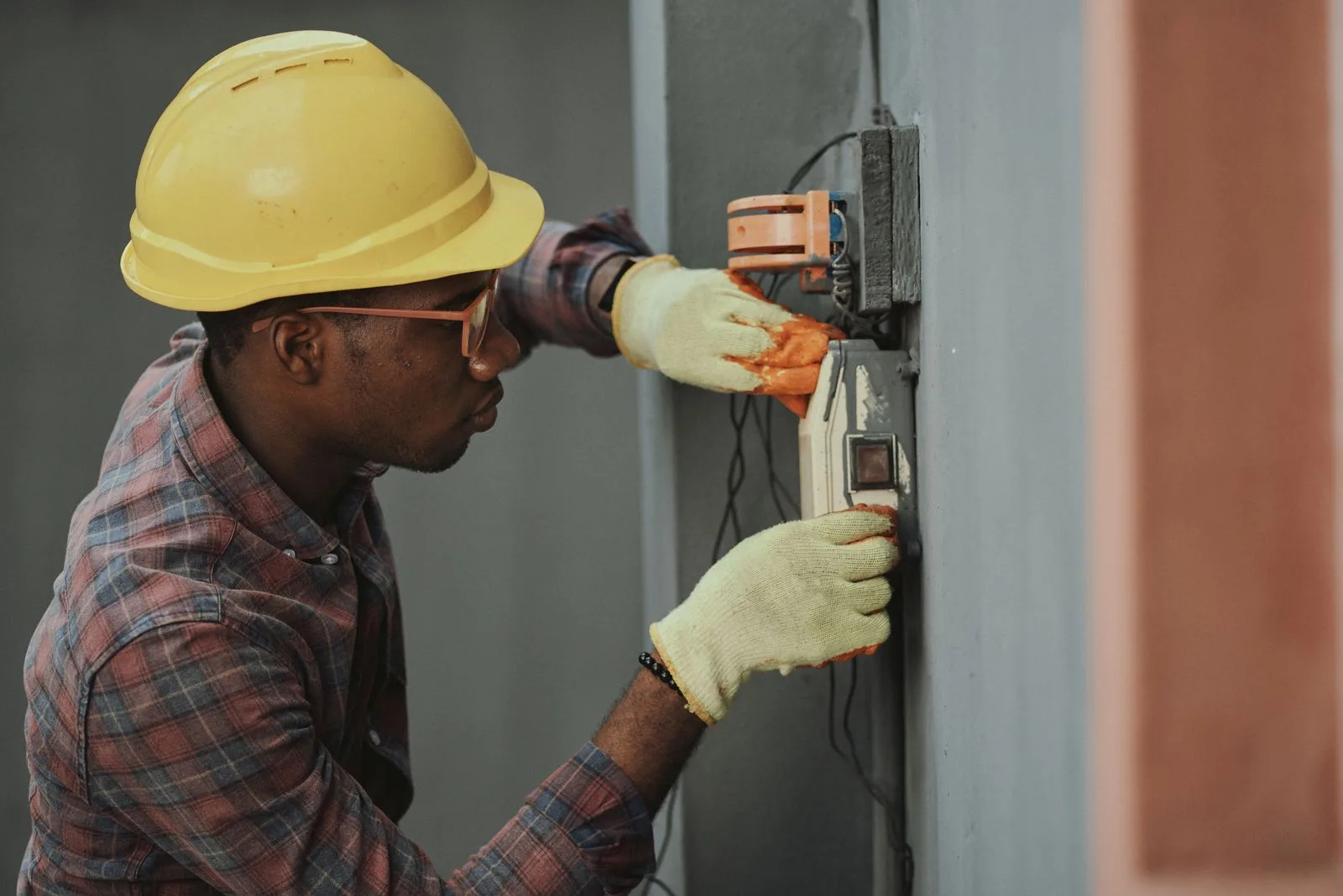 Electricista con casco y guantes trabajando en una instalación eléctrica